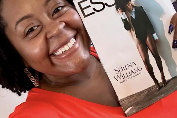 Photo of Shemeka Thorpe wearing red shirt and holding up a copy of Essence magazine