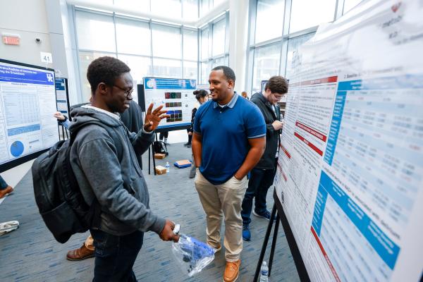 Students discussing research displayed on posters