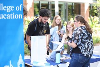Students at a College of Education table outdoors