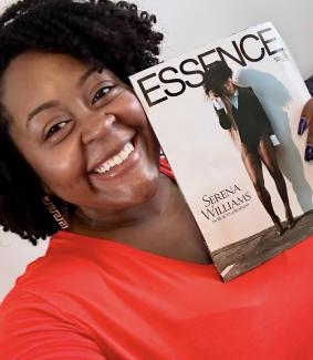 Photo of Shemeka Thorpe wearing red shirt and holding up a copy of Essence magazine