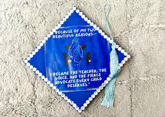 Photo of a mortar board that says "Because of my two beautiful reasons... I became the teacher, the voice, the fierce advocate every child deserves."