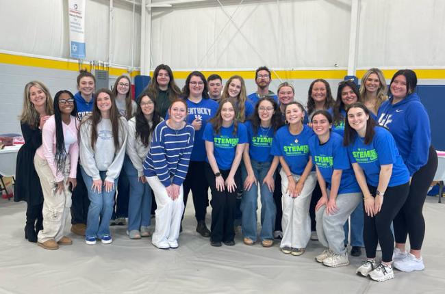  Group photo of elementary education and STEM education students who helped lead interactive activities for students and their families this semester during a Family STEAM Night event at Woodhill Community Center. Students are standing in two rows, and smiling at the camera.