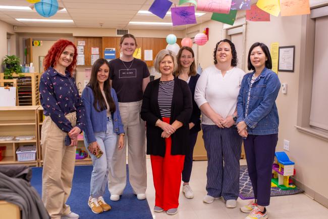 Seven people stand and pose for a photo in a daycare room at the UK Early Childhood Lab.