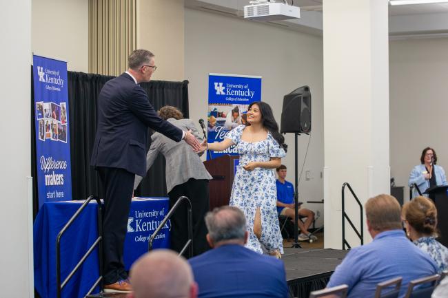 A student accepts a pin from UK College of Education Dean Nick Pace