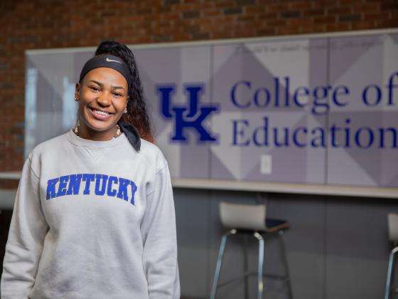 Student standing in front of the College of Education sign in the Dickey Hall Lobby