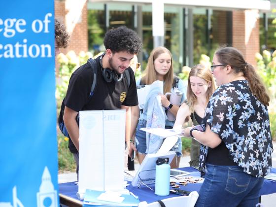 Students at a College of Education table outdoors